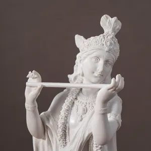 Macro detail of white Krishna resin statue with intricate crown and flute playing pose