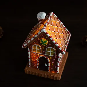 Close-up of lighted Christmas gingerbread house ornament with warm LED glow and snow detail