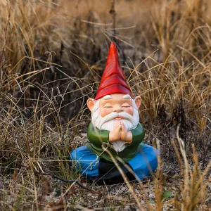 Garden gnome statue in meditation pose with red hat and green shirt for outdoor decor