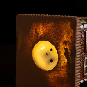 Close-up of the warm LED light and toggle power switch at the base of the resin gingerbread house