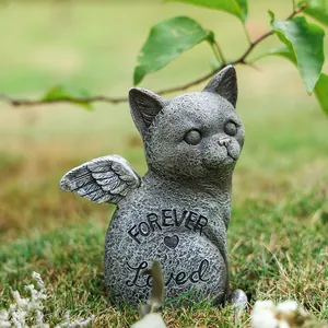 Détail d'une pierre commémorative chat ange ailé avec texte gravé sur de l'herbe verte