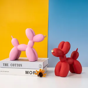 Détail de figurines chiens ballons en résine mate rose et rouge sur support moderne
