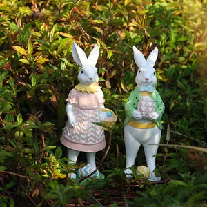 Estatuas de conejitos de Pascua de resina con trajes de lunares en un jardín natural