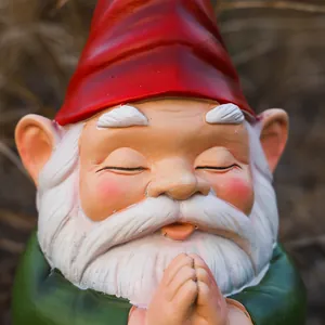 Close-up of meditating garden gnome face with red hat and white beard detail
