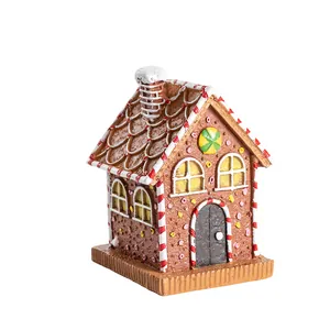 Charming resin gingerbread house ornament with snow-capped roof and candy details