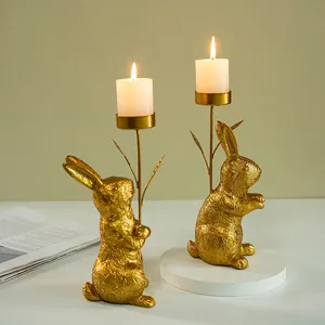Detail of golden resin rabbit candle holders with leaf textures and lit pillar candles