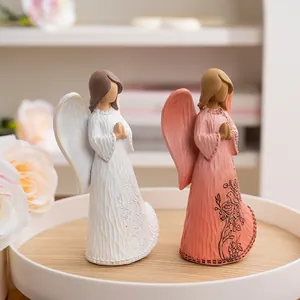 Macro detail of hand-carved resin angel figurines with floral embossing and bird motif