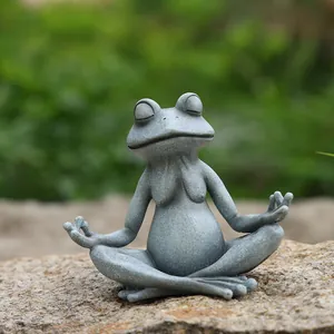 Dettaglio della statua di rana yoga in resina grigia su sfondo di roccia naturale