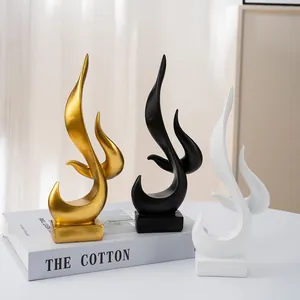 Close-up of abstract flame resin statues in gold, black, and white on square bases