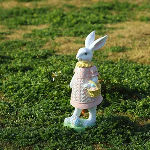 Detalle de figura de conejo de Pascua con vestido rosa y cesta en el jardín