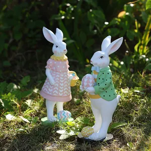 Detalle de estatuas de jardín de conejitos de Pascua con huevos sobre césped verde