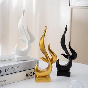 Close-up of three abstract flame resin sculptures in matte white, gold, and black finishes