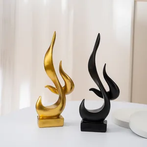 Modern abstract flame art sculptures in gold and matte black finish on white table