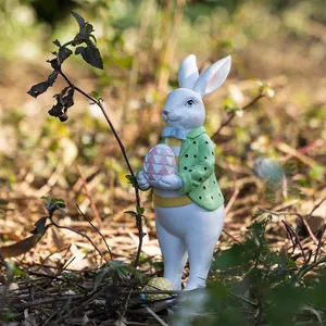 Figura de conejo de Pascua con chaqueta de lunares y huevo rosa en un entorno de jardín