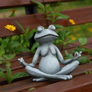 Dettaglio di una statua di rana yoga meditante su una panchina di legno in un giardino verde