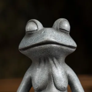 Close-up of meditating female frog statue with textured stone-like resin finish