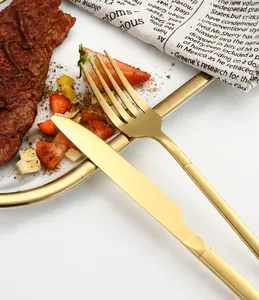 Primer plano de cuchillo y tenedor de filete en acero inoxidable oro mate en plato