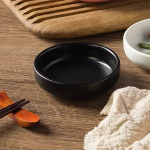 Minimalist matte black ceramic sauce dish on a rustic wooden table setting