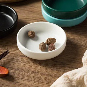 Close-up of matte ceramic sauce dishes in white, green and blue on a wooden table