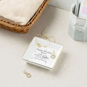Detail of square ceramic jewelry dish with gold rim and birthday message for mom