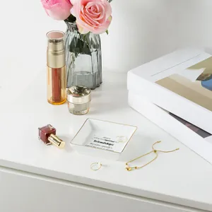 Detail of square white ceramic jewelry tray with gold rim and friendship quote