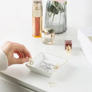 Macro detail of square ceramic jewelry tray with gold edge and mother birthday message
