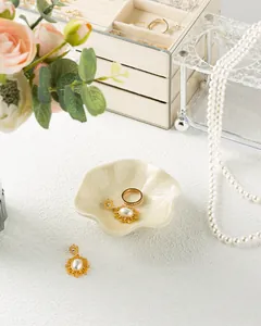 Detail of petal-shaped ceramic jewelry dish holding a ring and pearl earrings