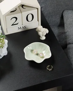 Ceramic lotus leaf jewelry tray holding pearl earrings and a gold open ring