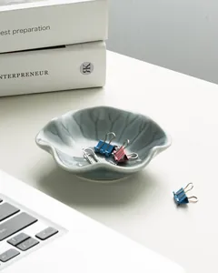 Detail view of the ceramic lotus leaf storage tray holding stationery on a white desk