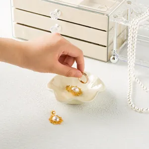 Ceramic jewelry tray with vintage pearl earrings and gold ring on textured surface