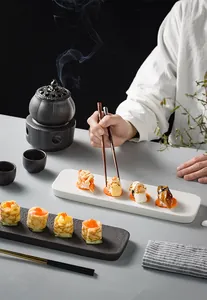 Close-up of rectangular ceramic sushi plate with textured white rock and black wood finish