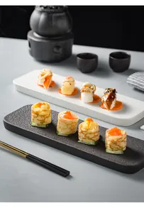 Close-up of minimalist rectangular ceramic sushi trays with matte rock texture