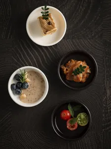 Top-down view of black and white ceramic sauce dishes on a rustic dark wooden surface