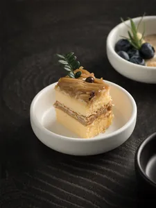 Detail shot of a Mont Blanc cake served in a white ceramic sauce dish on dark wood