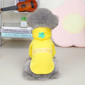 Detail of yellow banana pet hoodie with green flower on hood and white lettering