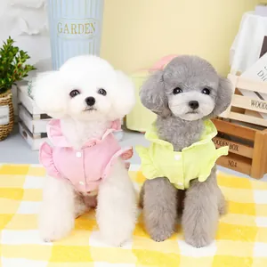 Pink and lime green ruffled pet shirts for small dogs shown in a cozy garden setting