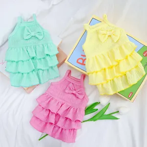Close-up of tiered ruffled pet dresses in mint green, soft yellow, and bright pink colors