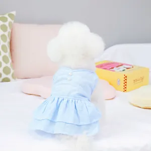 Détail d'une robe bleu clair pour animaux avec boutons en perles et ourlet à volants