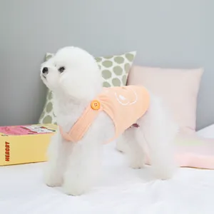 Close-up of orange waffle knit pet harness vest with smiley face on a white dog