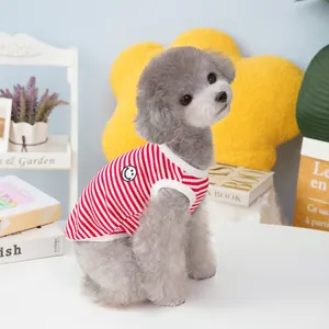 Red and white striped dog vest with smiley patch on gray poodle in cozy home setting