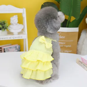 Detail view of yellow layered ruffle pet dress with a bow on a grey poodle