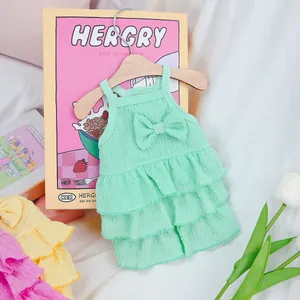 Close-up of mint green tiered pet dress with ruffled texture and bow on a wooden hanger