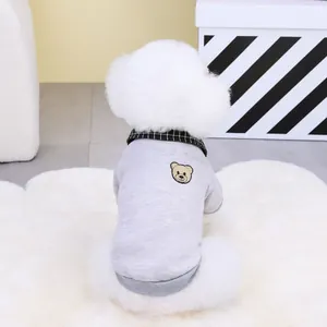 Detail of gray pet sweater with bear embroidery and checkered collar on a white dog