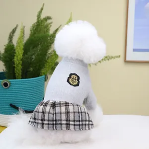 Plaid pet dress with grey knit top and crown emblem for small dogs in a home setting