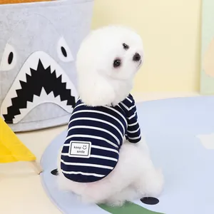 Detail of blue striped dog t-shirt with keep smile patch on a small white dog