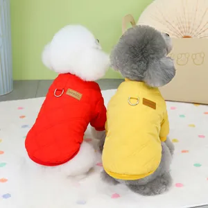 Close-up of quilted pet winter vests in red and yellow with metal D-rings and tags