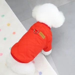 Detail of red quilted dog vest with metal D-ring and leather tag on a white dog