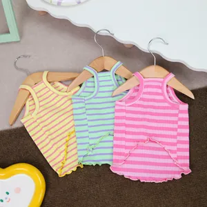 Three colorful striped pet tank tops with ruffled hems hanging on wooden hangers