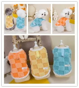 Detail of checkered plush pet vest with metal D-ring leash attachment and pom-pom trim