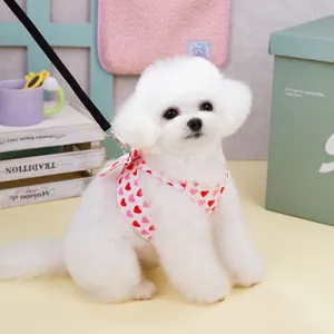 Pink heart print dog harness and leash set with bow detail on a small white puppy